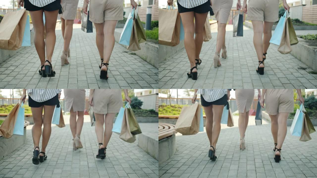 后视图女性双腿慢动作带着纸袋在户外行走在夏季城市购物