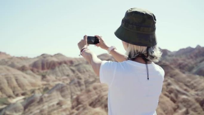 年轻的亚洲妇女在国家公园使用手机拍摄风景照片