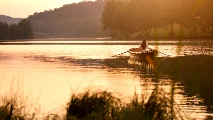 日落时，慢动作年轻女子在船上，灯光划过湖面