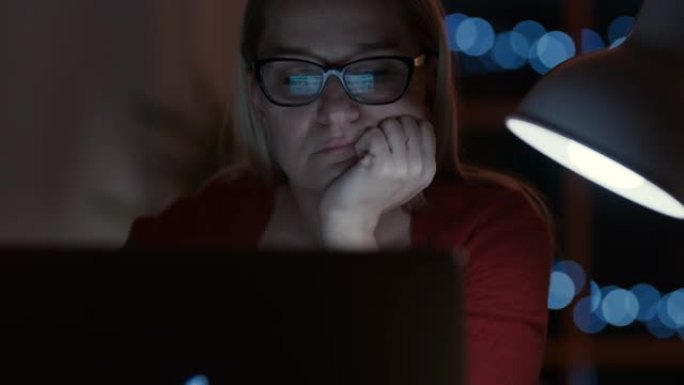 DS女人晚上在笔记本电脑上工作时感到无聊