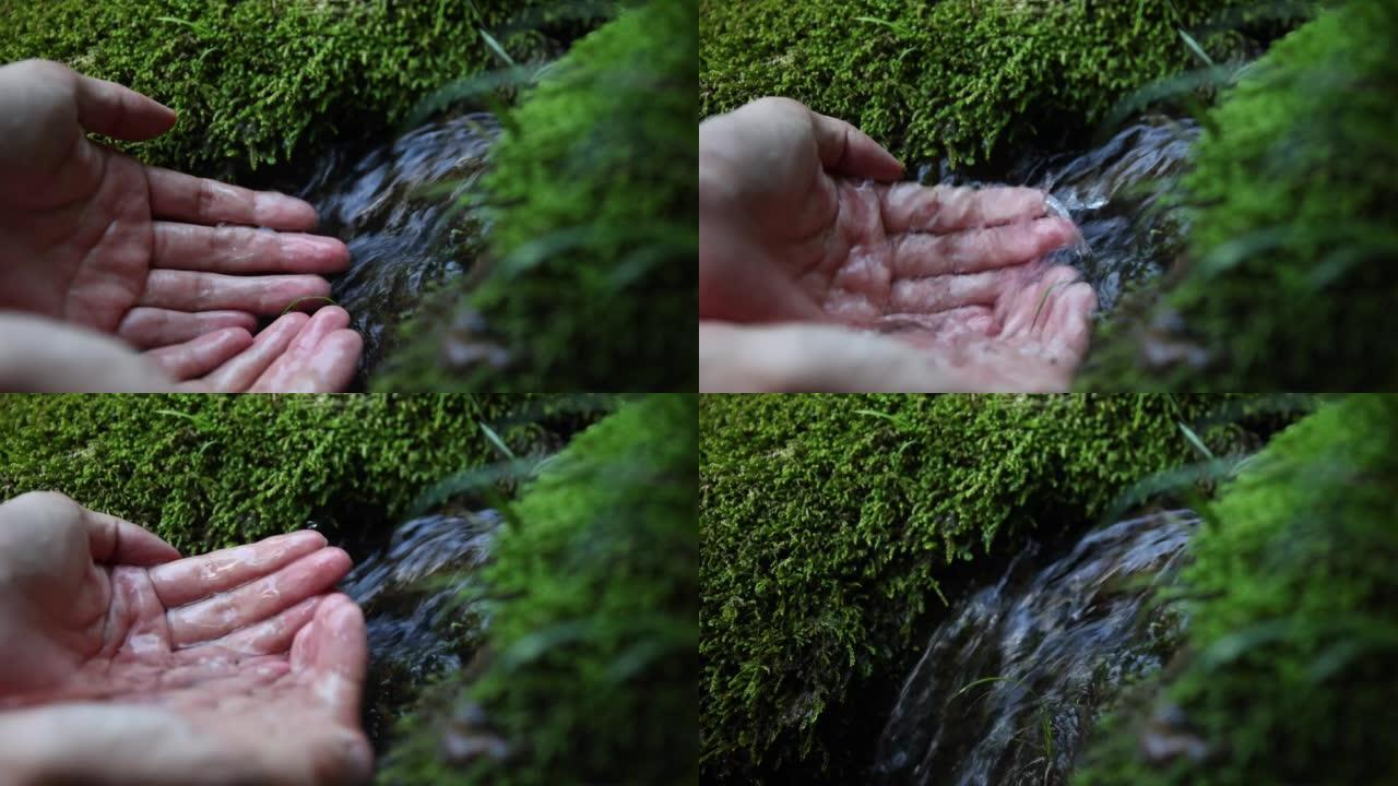 人类的手触摸下降的溪流水