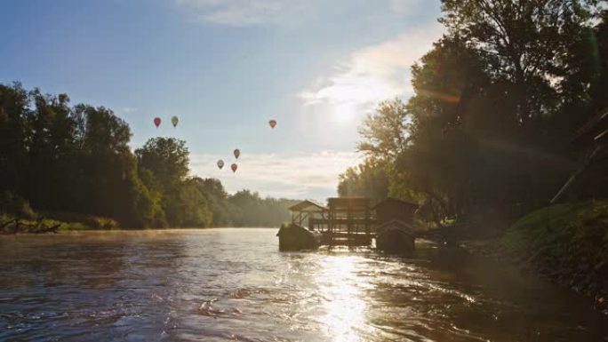 热气球在田园诗般的河上晴朗的蓝天中飞行