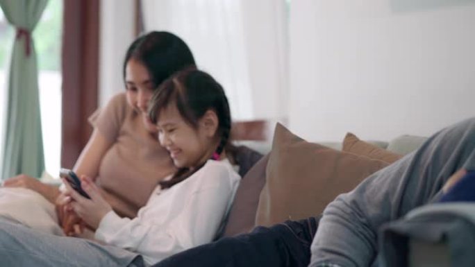 4K UHD平移转移焦点: 亚洲女孩和她的妈妈一起读童话故事书，而爸爸在冠状病毒新型冠状病毒肺炎大流