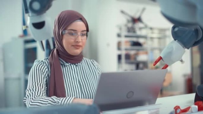 Hijab的中东工程师在Modern Office的笔记本电脑上对机械臂和编程进行了深入分析。优化自