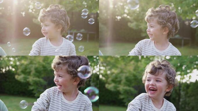 小男孩在花园追逐和破裂泡沫中玩耍