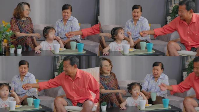 一群亚洲老年人喜欢在家里的客厅里聊天和照顾孙子