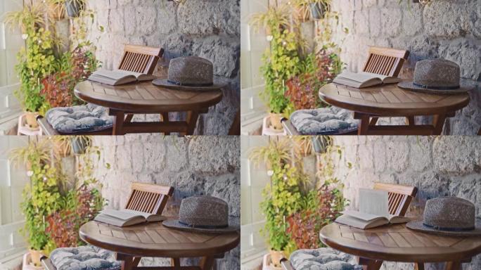 SLO MO在海边房屋的阳台上的桌子上打开的书和帽子