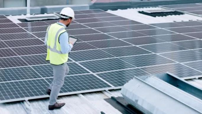 电工检查他工作的建筑物屋顶上的太阳能电池板技术。戴着安全帽的专业工程师技术员仔细观察他的现代可再生能