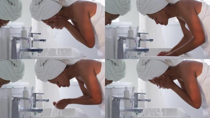 非裔美国妇女在家里的浴室水槽里洗脸