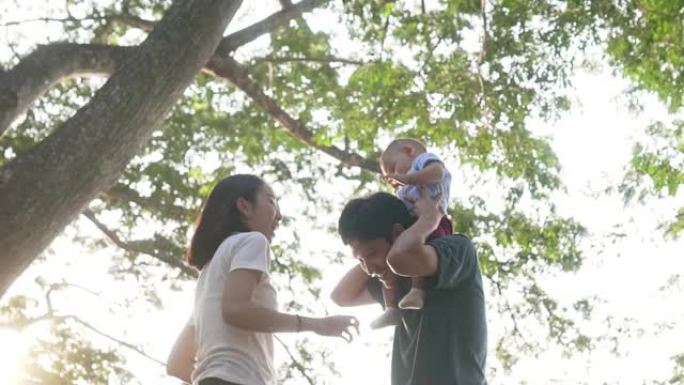 快乐的亚洲家庭，儿子在公园的爸爸肩膀上开心，慢动作