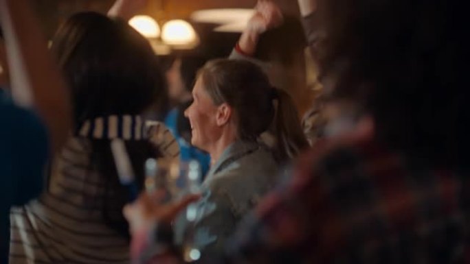 一位穿着牛仔裤外套的美丽年轻女性的肖像站在酒吧里的体育迷人群中，观看直播。一群人庆祝球队进球并赢得冠
