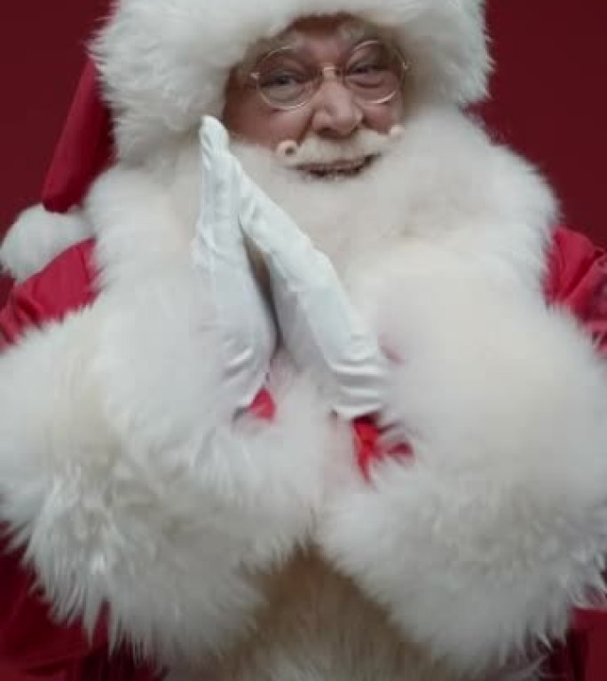 红色背景上庆祝圣诞老人的垂直视频，他在跳舞，揉着手掌，竖起大拇指