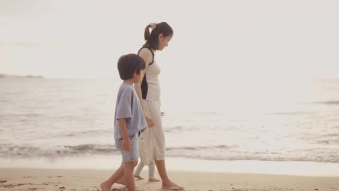 在阳光明媚的日子里，年轻的亚洲妇女和两个可爱的孩子在海边散步。