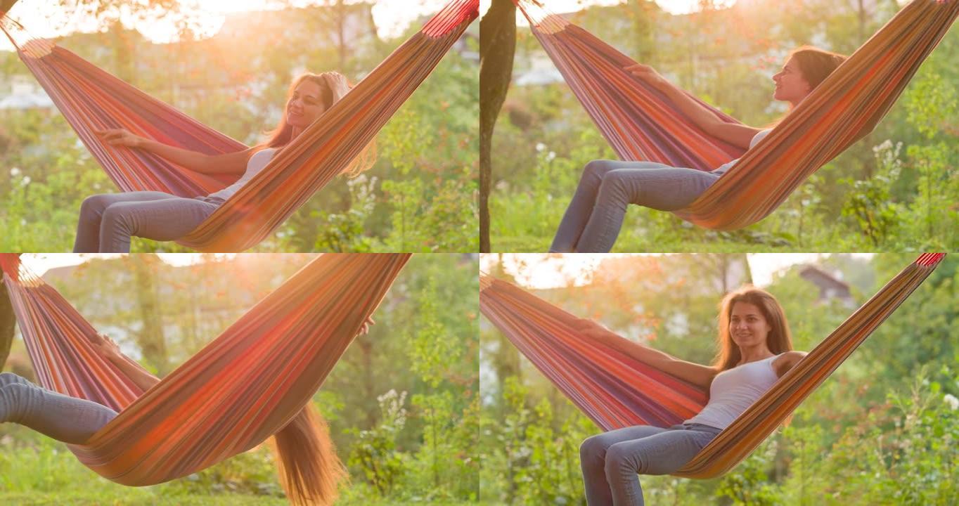 快乐的年轻女子在大自然中享受夏天，在吊床上摇摆