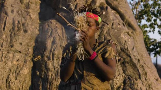 哈扎 (Hadza) 狩猎采集者部落成员以缓慢稳定的方式在草地上吹来，以传统的方式点燃坦桑尼亚