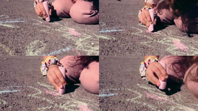 小女孩用粉笔在柏油路上画画