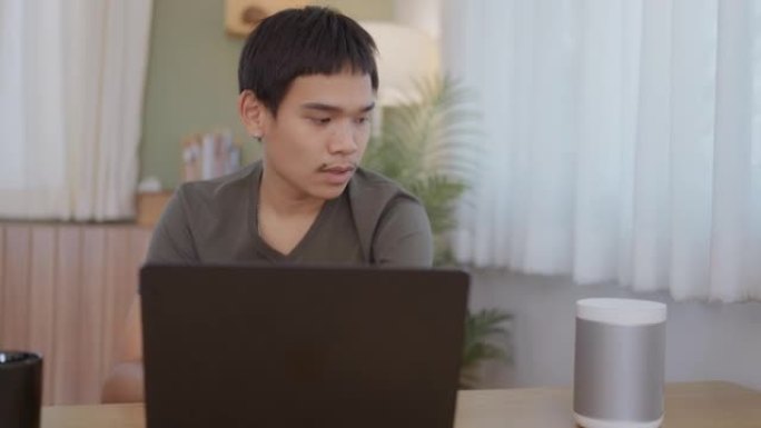 手臂残疾的快乐年轻人在家用笔记本电脑工作。