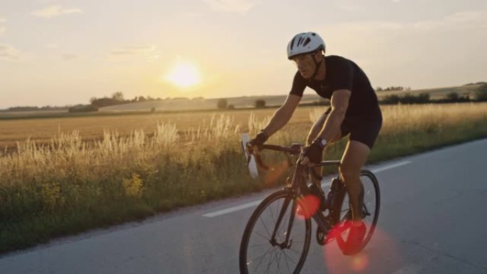 SLO MO专业自行车手在日落时快速驶过乡村