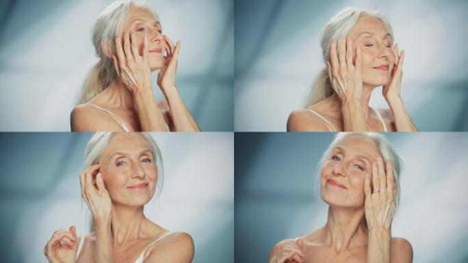 中等肖像: 高级女人看着相机，抚摸美丽的脸，微笑。老年女性，灰发茂盛，蓝眼睛，皮肤柔软。尊严的自然护