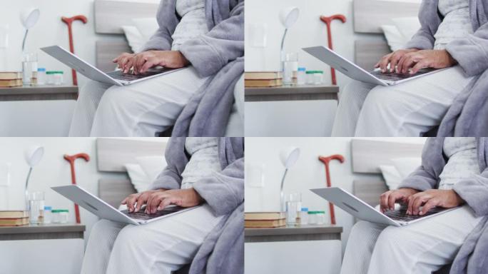 非裔美国高级女性坐在家里的床上使用笔记本电脑的中段