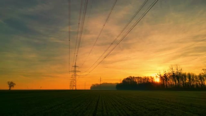 日落时田园诗般的乡村上的电塔和电线