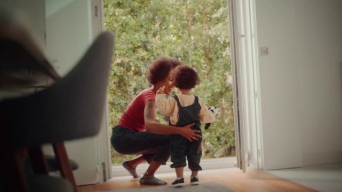 慈爱的母亲在现代家庭客厅拥抱和抱着可爱的男婴，在露台上出去。开朗的保姆养育孩子。童年、新生活、为人父