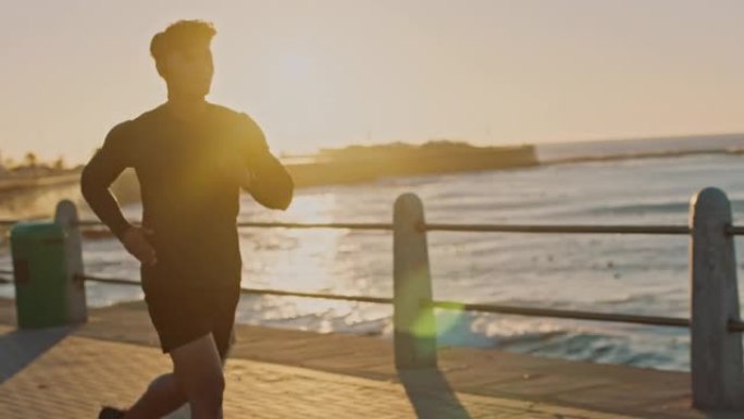 男子，音乐耳机或在日落海滩，海洋或海洋中跑步，进行医疗保健锻炼，马拉松训练或有氧运动。慢动作的跑步者