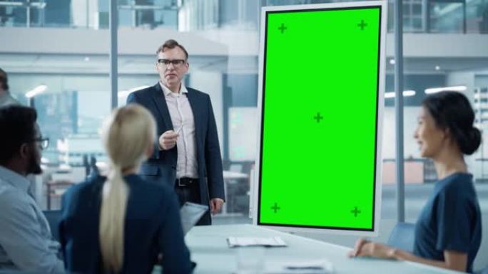 公司运营经理为一组经济学家举行会议演示。成年男性使用带有垂直绿色屏幕模拟显示的数字白板。人们在商务办