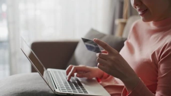 年轻女子在家使用信用卡进行在线购物