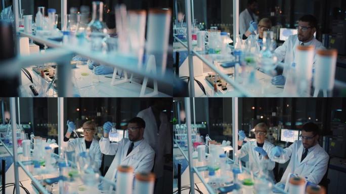 女性和男性医学研究科学家在用液体样品和带有固体样品的烧杯进行实验时进行了交谈。现代科学实验室。
