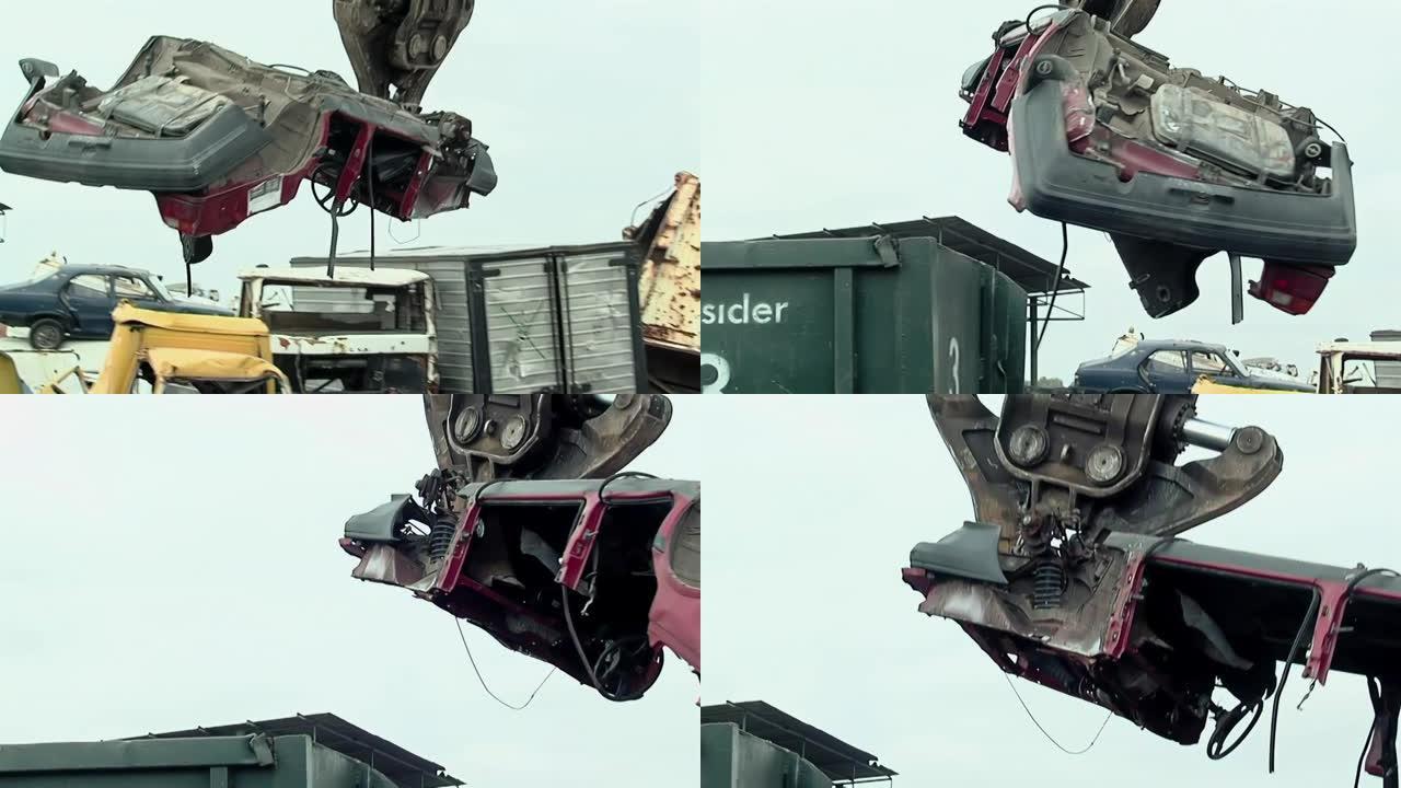 机械起重机的液压爪在废料场举起一辆废旧汽车。