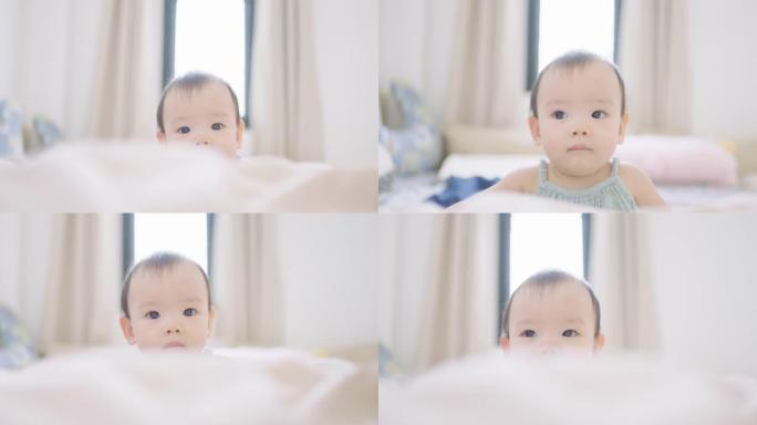 无辜的女婴在卧室的毯子后面看着相机