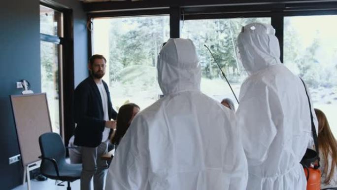 摄像机跟随两名穿着白色医疗套装的医护人员进入办公室商务会议，在新型冠状病毒肺炎期间关闭。