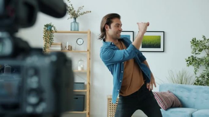 创造性的男性视频记录器记录舞蹈动作，并在公寓室内使用摄像头交谈