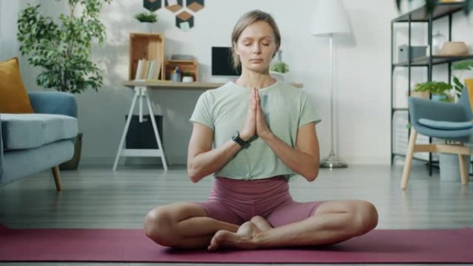 穿着运动服的放松女孩坐在荷花姿势冥想，闭着眼睛坐在瑜伽垫上。