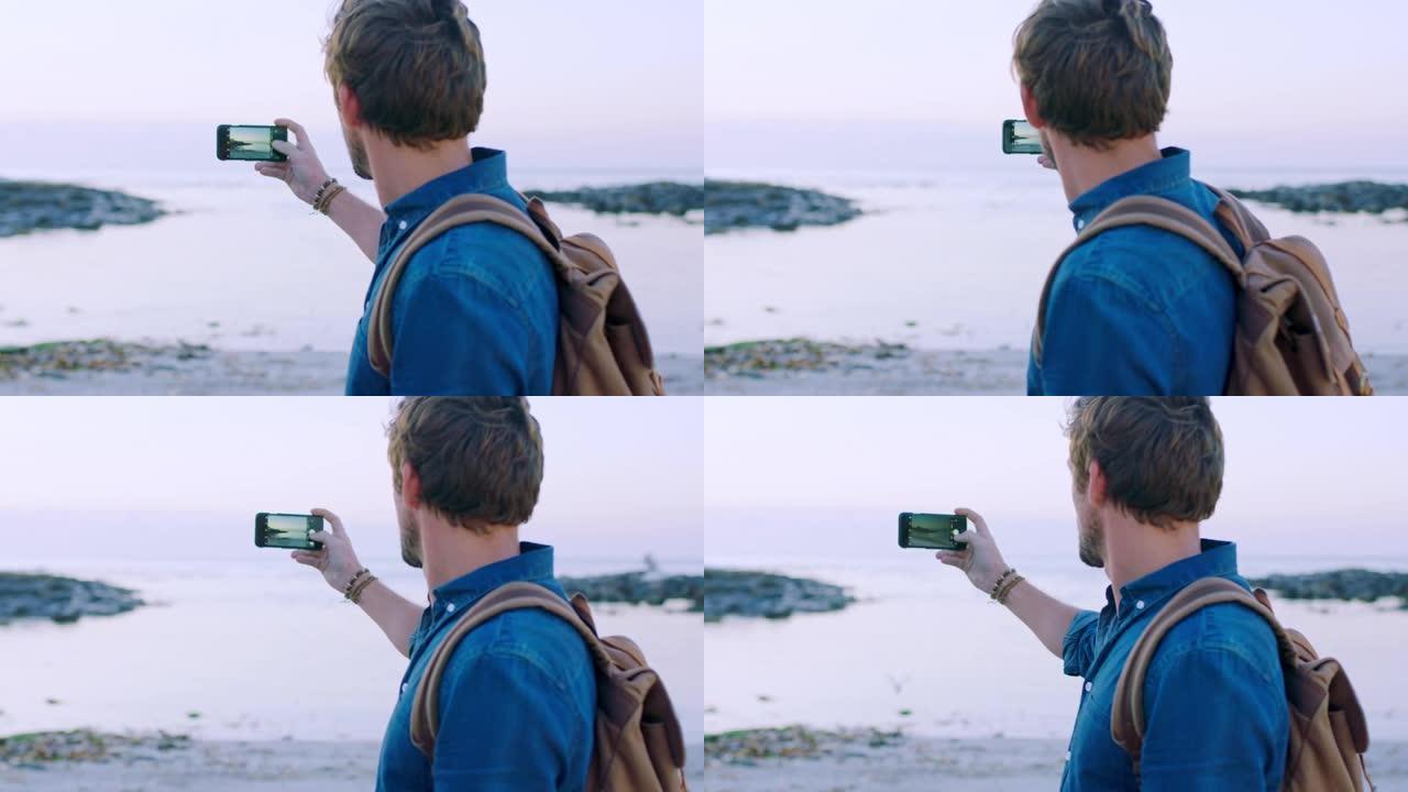 男人，旅行和电话在海滩上拍照或录制视频，度假时背着背包自由和冒险。男性与智能手机在海上更新博客与旅程