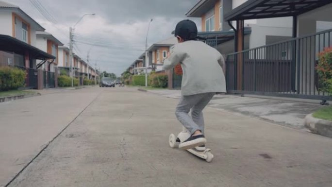 快乐的小男孩在城市骑踏板车。