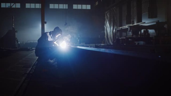 重工业工程工厂内部，工业工人使用焊接机并在金属管上工作。安全制服和安全帽制造金属结构的承包商。