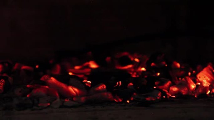 黑色不锈钢木炭耙移动燃烧的木炭，而一个男人正在准备阿根廷潘帕斯州的传统烧烤 “Asado”。4k分辨