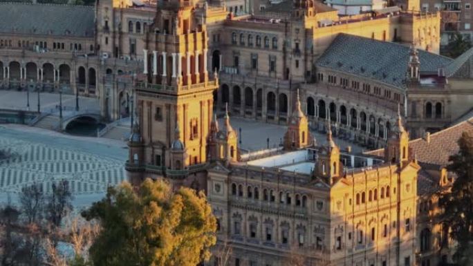 在西班牙塞维利亚的西班牙广场周围飞行。早晨的阳光照射下的西班牙广场综合大楼的空中远程拍摄
