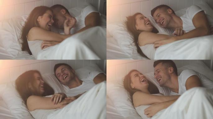 那对年轻幸福的夫妇在床上大笑。慢动作