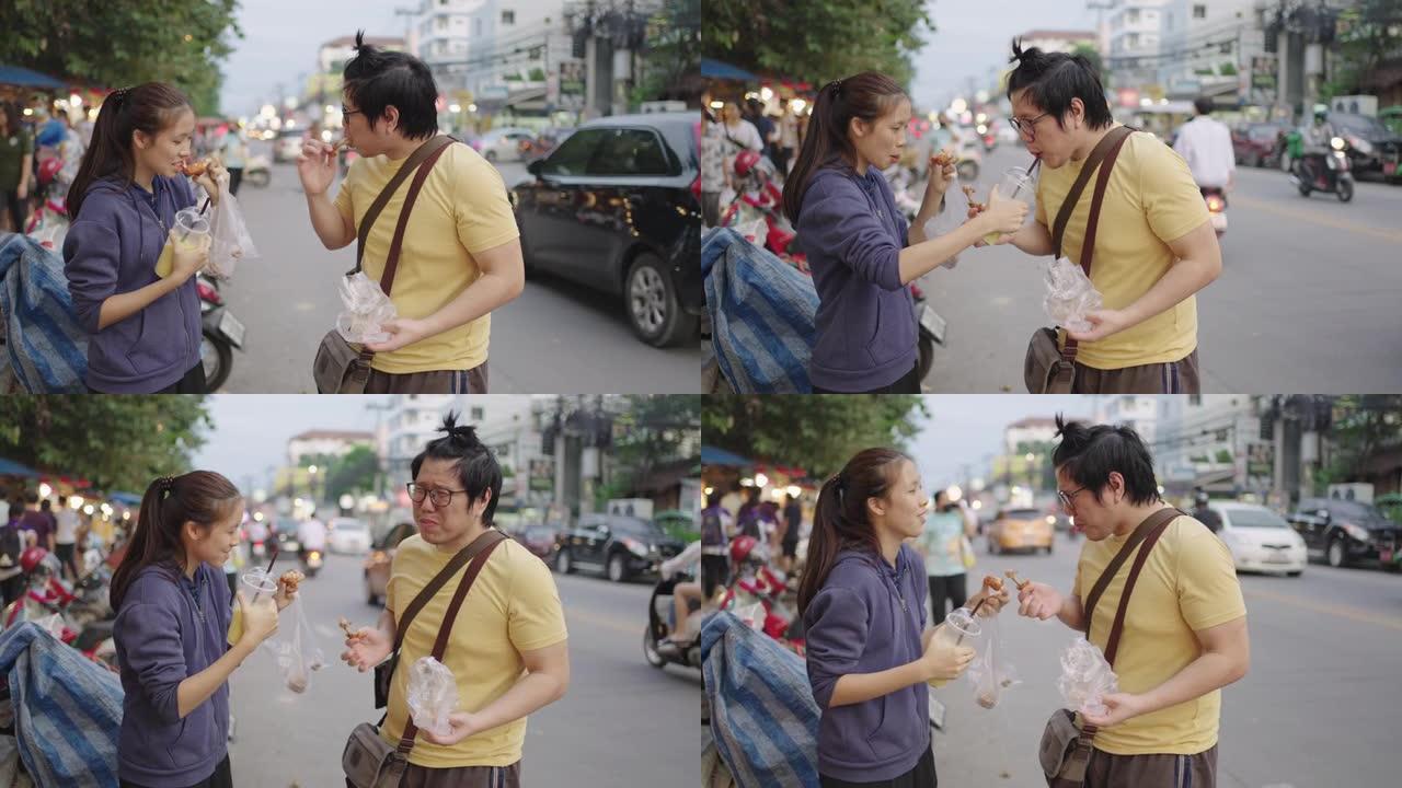 亚洲男女在路边分享街头食物。