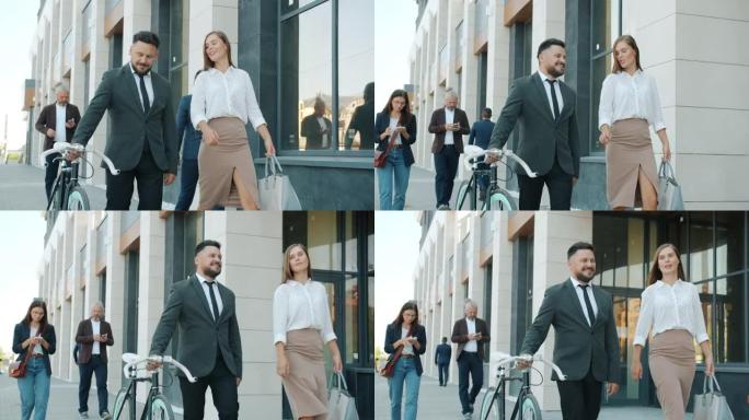 男人和女人的慢动作同事在城市街道上行走并手持自行车