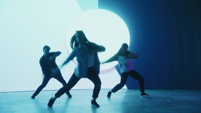 由三名专业舞者组成的多元化小组，在工作室环境中的虚拟制作期间，在带有蓝色VFX动画的大Led墙屏幕前