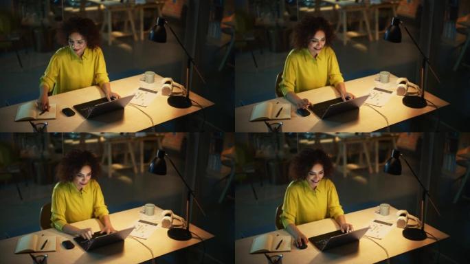 美丽的中东经理晚上坐在创意办公室的办公桌前。年轻时尚女性在营销机构使用笔记本电脑。在笔记本上写下重要