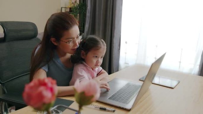 母亲Python开发人员使用笔记本电脑远程编码在家工作并照顾女儿