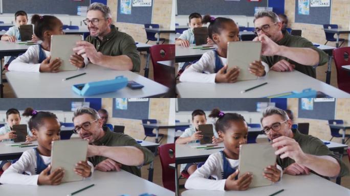 多元化的男老师使用平板电脑帮助坐在教室里的女学生