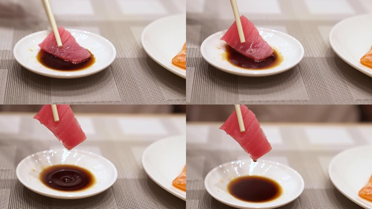 4K UHD慢动作手持: 用筷子将金枪鱼生鱼片浸入酱油碗中。日本美食美食，亚洲文化。健康食品概念。