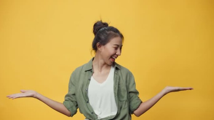 自信美女亚洲青年女士站在孤立的黄色背景上张开的手掌指向复制spac显示空旷的空间，展示广告微笑兴奋。