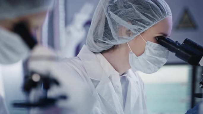 研究期间的女性微生物学家。在未来实验室中使用显微镜。背景研究伙伴